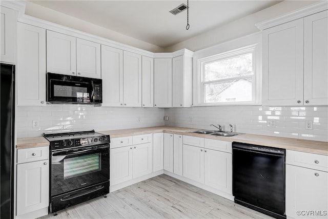 kitchen featuring white cabinetry, sink, black appliances, and wooden counters