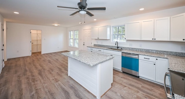 kitchen with white cabinetry, sink, stainless steel dishwasher, and light stone counters