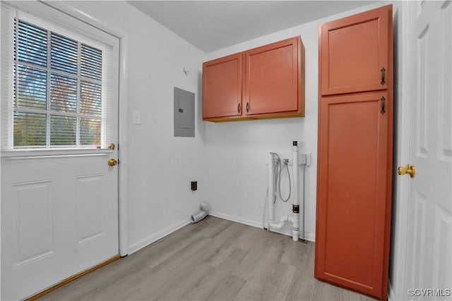 clothes washing area featuring light hardwood / wood-style floors, cabinets, and electric panel