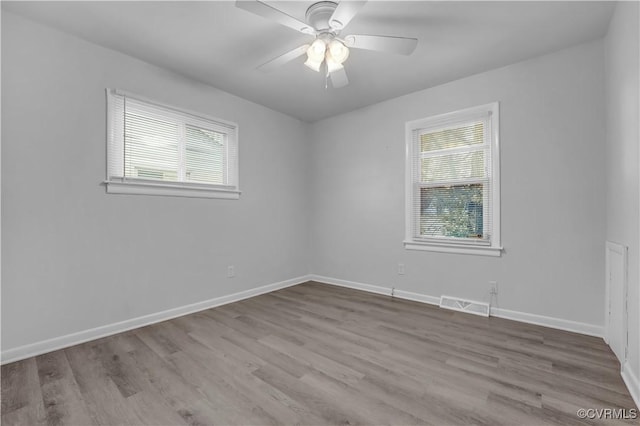 empty room with ceiling fan, a wealth of natural light, and light hardwood / wood-style floors