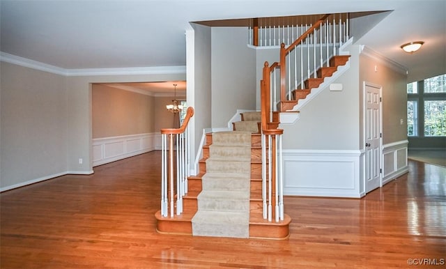 staircase featuring hardwood / wood-style floors, a chandelier, and ornamental molding