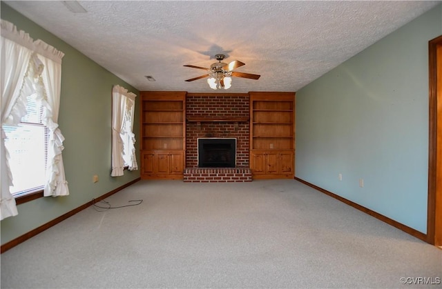 unfurnished living room featuring light carpet, a brick fireplace, ceiling fan, built in shelves, and a textured ceiling