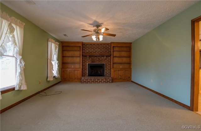 unfurnished living room featuring light carpet, a brick fireplace, a textured ceiling, ceiling fan, and built in features