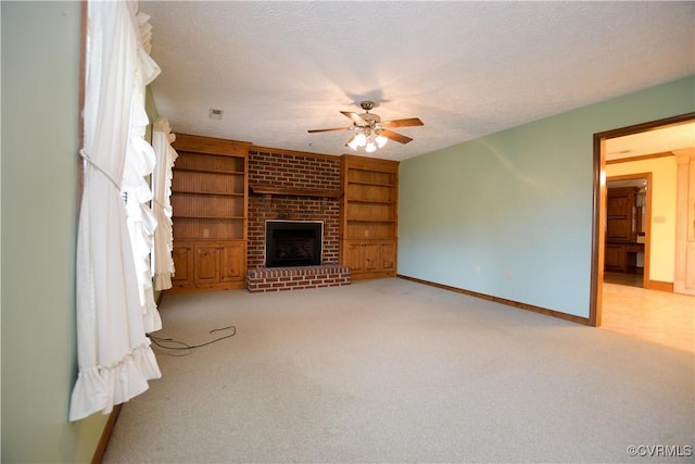 unfurnished living room with a brick fireplace, ceiling fan, built in features, a textured ceiling, and light colored carpet