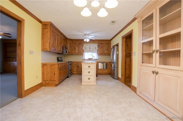 kitchen featuring a textured ceiling, ceiling fan with notable chandelier, a kitchen island, and stainless steel appliances