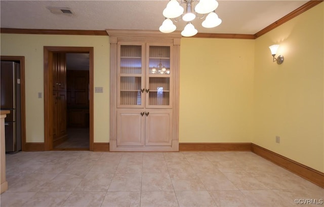 unfurnished dining area with light tile patterned floors, ornamental molding, a textured ceiling, and an inviting chandelier