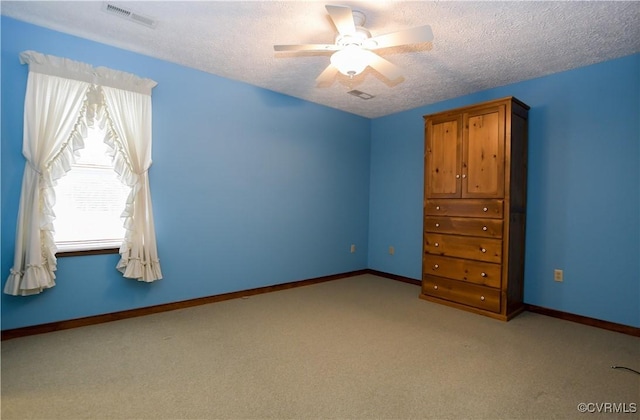 unfurnished bedroom featuring a textured ceiling, light colored carpet, and ceiling fan