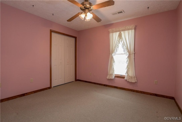 unfurnished bedroom with carpet, ceiling fan, a textured ceiling, and a closet