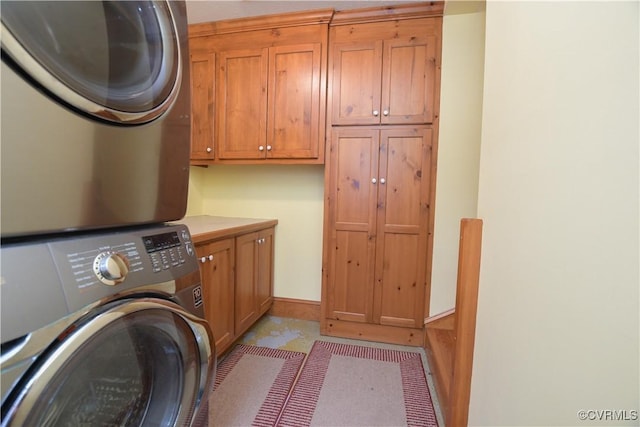 laundry room featuring cabinets and stacked washer and clothes dryer