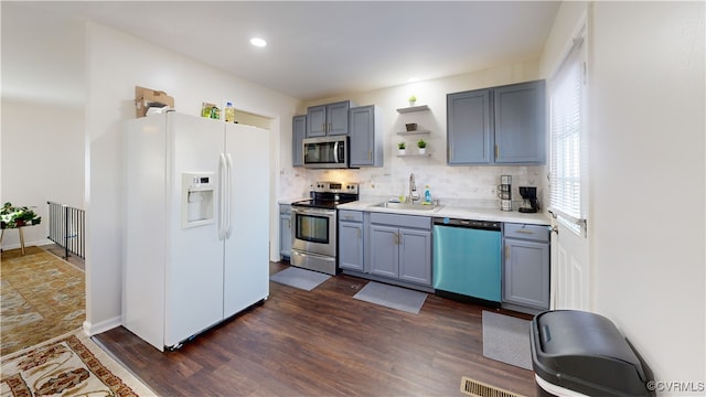 kitchen featuring appliances with stainless steel finishes, sink, backsplash, and dark hardwood / wood-style flooring