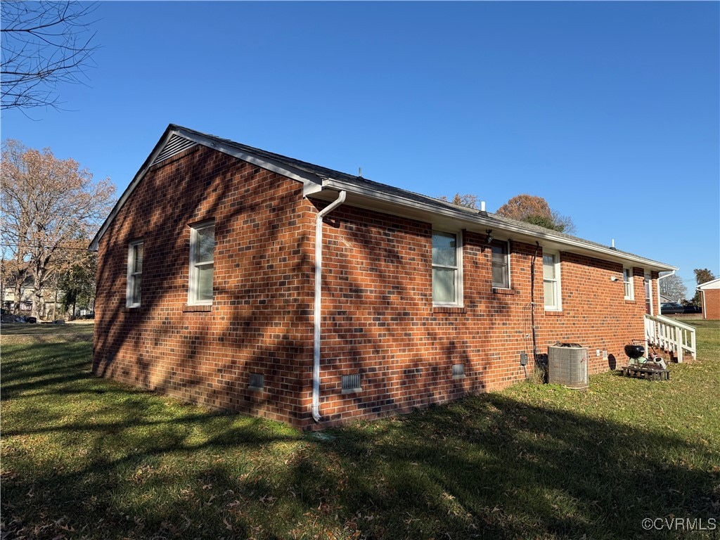 view of side of home with a lawn and central AC unit