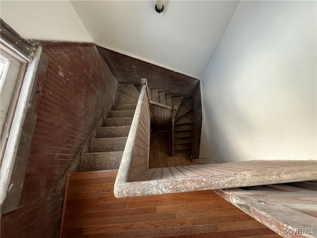 stairs with hardwood / wood-style floors and wooden walls