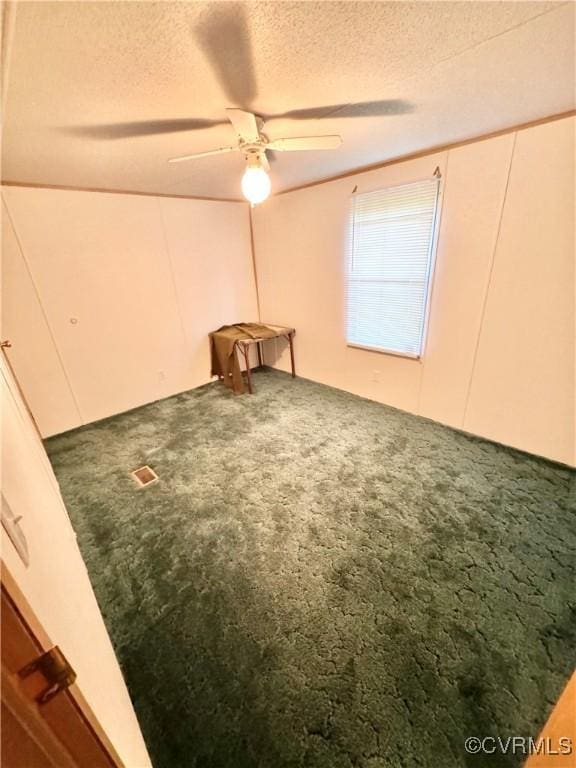 empty room featuring carpet flooring, ceiling fan, and a textured ceiling