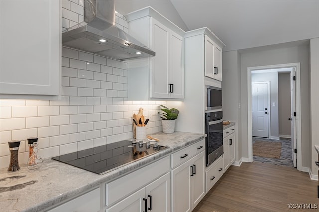 kitchen featuring backsplash, oven, wall chimney exhaust hood, black electric cooktop, and white cabinetry