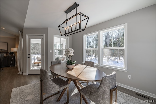 dining room featuring dark wood-type flooring, vaulted ceiling, and a notable chandelier