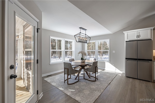 dining room featuring dark hardwood / wood-style flooring, vaulted ceiling, and a notable chandelier