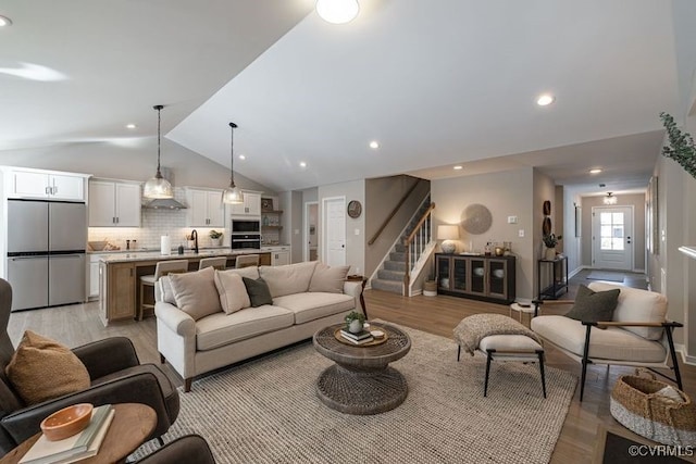 living room with light wood-type flooring, lofted ceiling, and sink