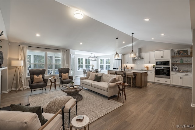 living room with a wealth of natural light, sink, dark hardwood / wood-style floors, and vaulted ceiling