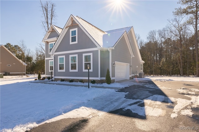 view of front of house featuring a garage, cooling unit, driveway, and board and batten siding