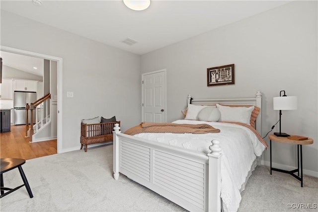 bedroom featuring stainless steel fridge, light colored carpet, and vaulted ceiling