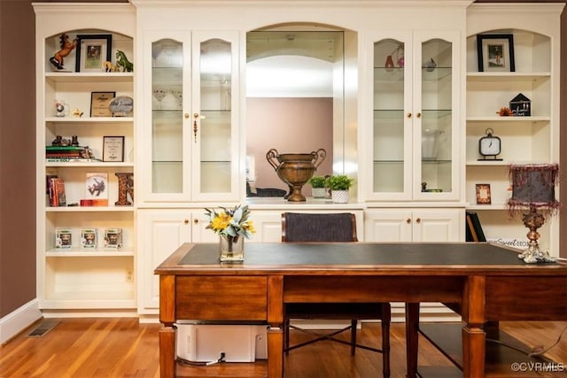 office space with built in shelves and wood finished floors