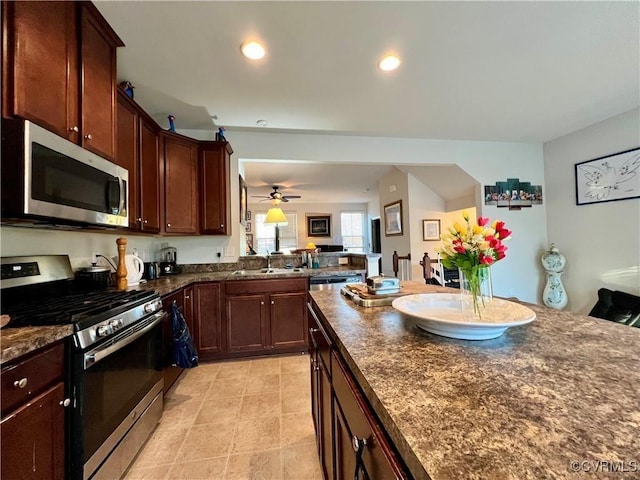 kitchen featuring dark stone countertops, ceiling fan, sink, and stainless steel appliances