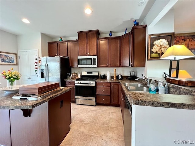 kitchen with dark brown cabinets, sink, a kitchen bar, and stainless steel appliances