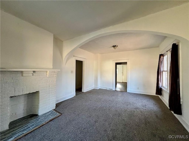 unfurnished living room with carpet flooring and a brick fireplace