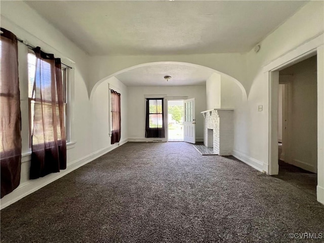 unfurnished living room with carpet floors and a brick fireplace