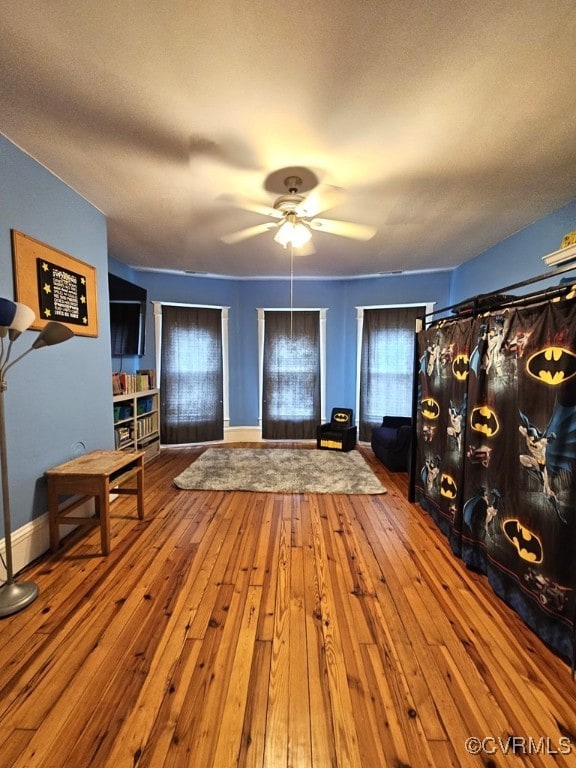 entrance foyer with a ceiling fan, baseboards, and wood-type flooring