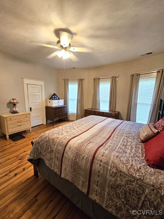 bedroom featuring hardwood / wood-style flooring, visible vents, and a ceiling fan