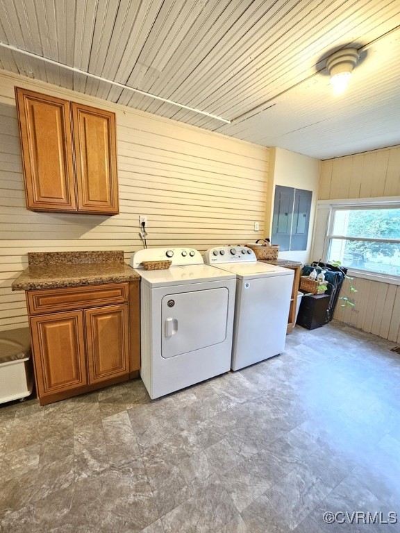 laundry room featuring washer and clothes dryer, wooden walls, electric panel, cabinet space, and wooden ceiling