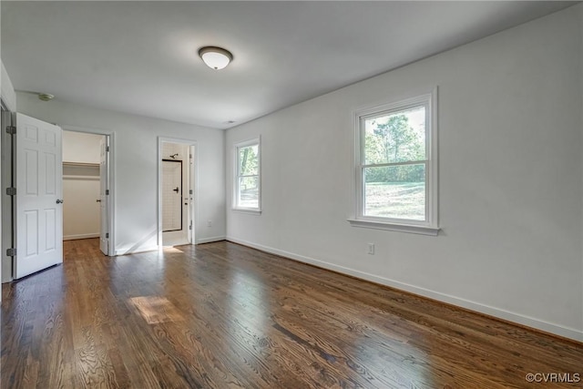 empty room featuring plenty of natural light and dark wood-type flooring