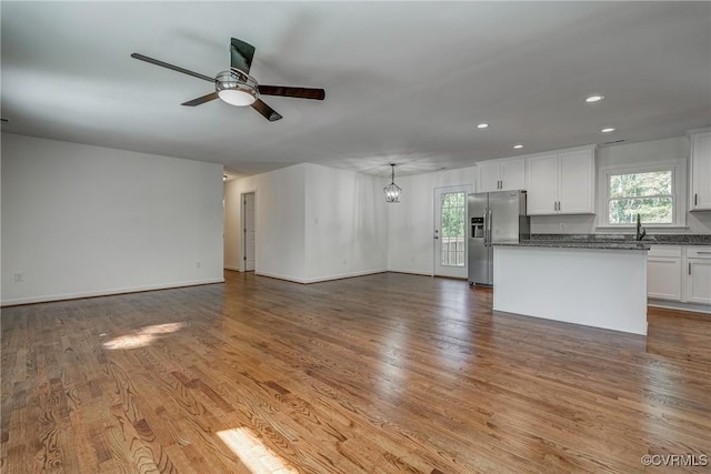 unfurnished living room featuring hardwood / wood-style floors, ceiling fan with notable chandelier, and sink