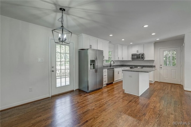 kitchen featuring white cabinetry, dark wood-type flooring, pendant lighting, a kitchen island, and appliances with stainless steel finishes