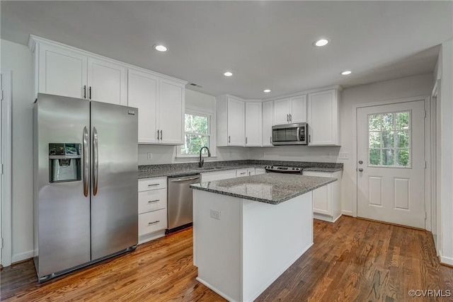 kitchen featuring a center island, sink, dark stone countertops, white cabinetry, and stainless steel appliances