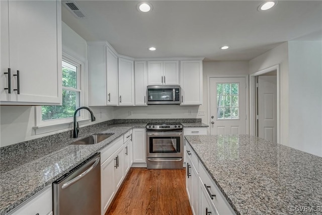 kitchen featuring appliances with stainless steel finishes, light stone counters, white cabinetry, and sink