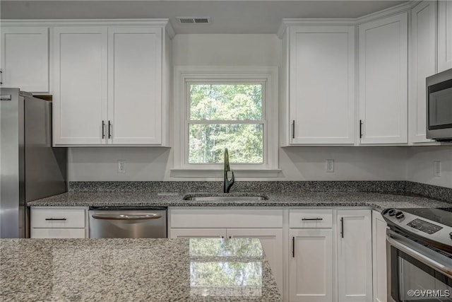 kitchen featuring appliances with stainless steel finishes, stone countertops, white cabinetry, and sink