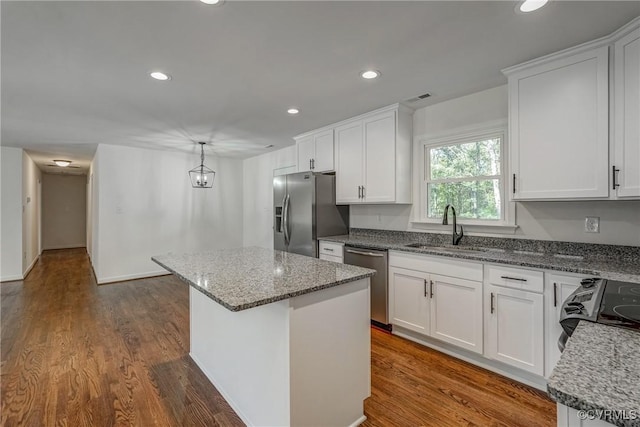 kitchen with stone counters, sink, stainless steel appliances, a kitchen island, and white cabinets