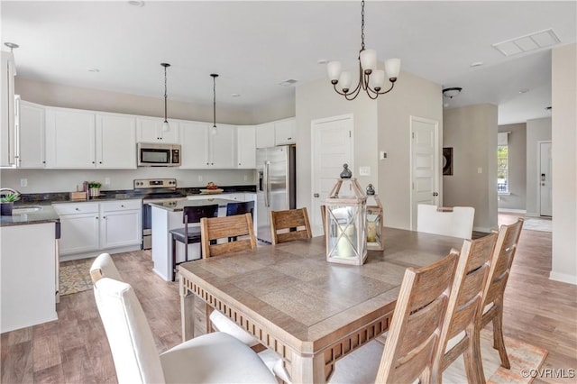 dining space featuring hardwood / wood-style flooring, sink, and an inviting chandelier