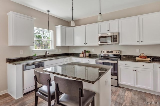 kitchen featuring sink, a center island, decorative light fixtures, a breakfast bar, and appliances with stainless steel finishes