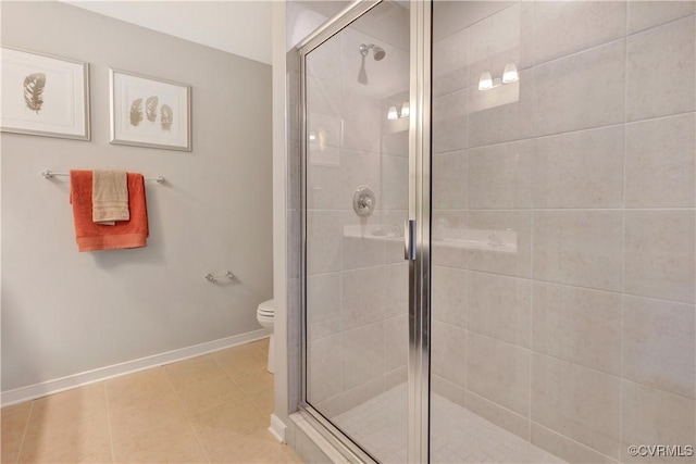 bathroom featuring tile patterned flooring, toilet, and a shower with shower door