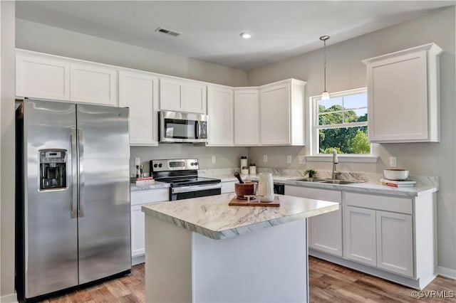 kitchen with white cabinetry, sink, hanging light fixtures, stainless steel appliances, and hardwood / wood-style floors