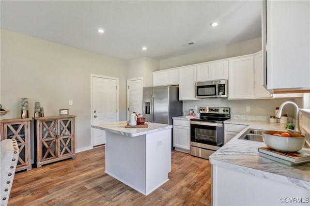 kitchen featuring appliances with stainless steel finishes, a kitchen island, sink, light hardwood / wood-style flooring, and white cabinetry