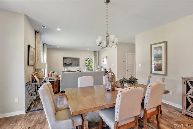 dining space with light hardwood / wood-style floors and an inviting chandelier