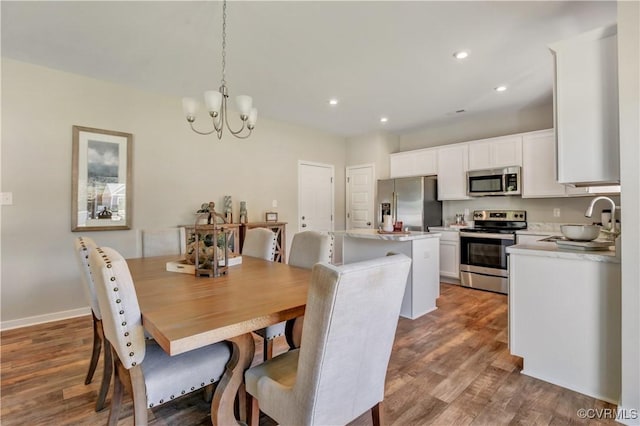 dining space featuring sink, a chandelier, and hardwood / wood-style flooring