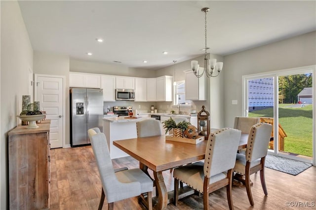 dining space featuring light hardwood / wood-style floors, a notable chandelier, and sink