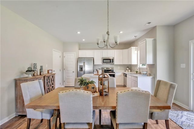 dining area featuring sink, a chandelier, and light hardwood / wood-style flooring