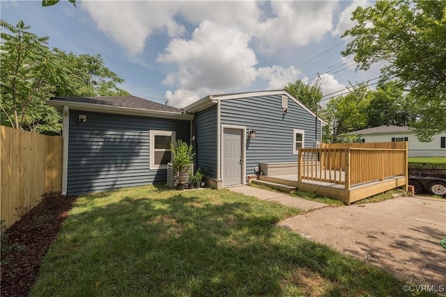 back of property with a deck and a lawn