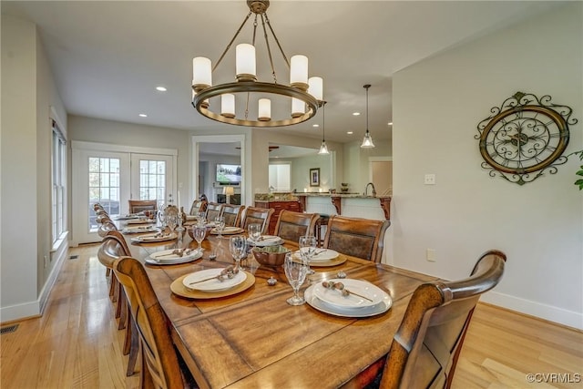 dining space featuring light hardwood / wood-style floors, french doors, and a chandelier